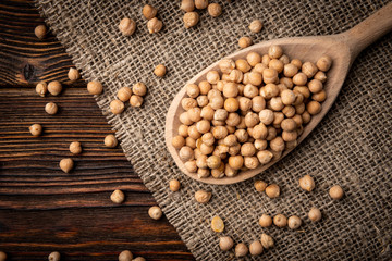 Chickpea in wooden spoon on dark wooden background.