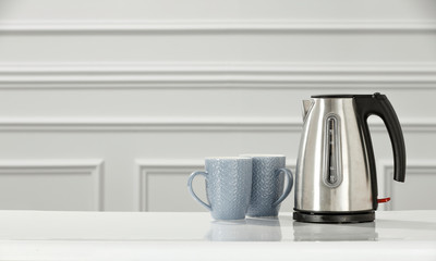 White wall with desk background and silver kettle. 