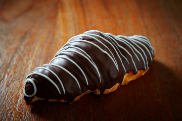 Chocolate coated croissant on wooden background 