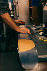 cropped view of worker using brush on ski in repair shop