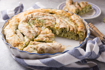Greek pie spanakopita  over concrete  background. Ideas and recipes for vegetarian or vegan  Spinach Pie from fillo pastry cut in slices. Copy space. Top view or flat lay.