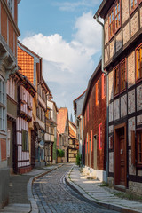 View of a narrow street with traditional colorful half-timbered houses in the old medieval town of Quedlinburg, part of UNESCO World Heritage Site, region Harz, Saxony-Anhalt, Germany.