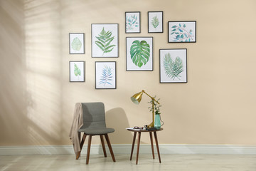 Beautiful paintings of tropical leaves on beige wall in room interior