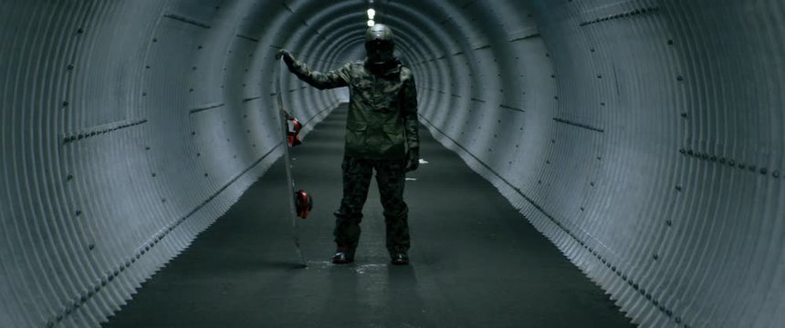 Portrait of a snowboarder in a full face protective helmet posing inside a dark narrow tunnel on a ski resort. 4K UHD RAW graded footage