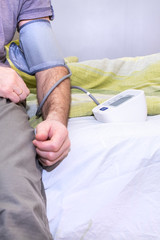 Tonometer, measuring blood pressure. Man's hand on the bed. Diagnosis of hypertension and tachycardia.