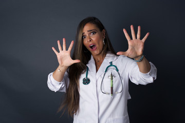 Dissatisfied doctor female model frowns face, has disgusting expression, shows tongue, expresses...