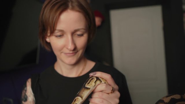 Woman holding python which is the sample for tattoo