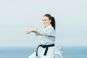Young female redhead karate fighter hitting a left punch © Mikel Taboada