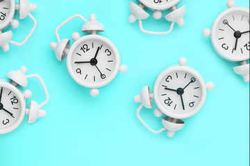 A pattern of many white classic alarm clocks in the form of a pattern on a blue background. Top...