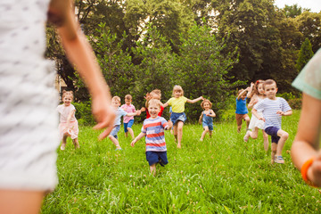 Fototapeta premium Group of children of boys and girls run in park on green grass
