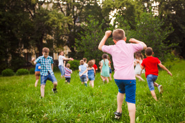 Back view of children running on green grass