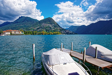 Motor Boats at the promenade of the luxurious resort in Lugano on Lake Lugano and Alps mountains in...
