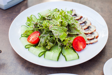 Closeup of a tasty fresh eel salad with arugula, lettuce and tomatos on white plate
