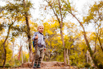 Naklejka na ściany i meble Lovely child boy enjoying nature in autumn park