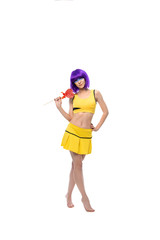 cheerful full-length portrait of a young girl in a purple wig and yellow clothes with a heart-shaped Lollipop on a white background