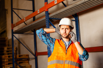 Warehouse worker in protective helmet talking on the phone