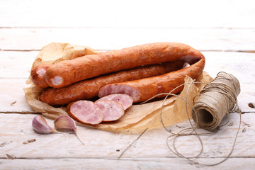 Rings of smoked pork sausage on a paper and wooden boards.