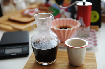 Manual brewing still life. Pouring filter coffee is served in decanter on bamboo board. Third wave specialty aesthetics