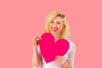 Studio portrait of a smiling young woman holding pink heart, romantic love, dating and Valentine's Day concept with copy space