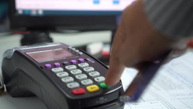 Using Credit card payment for purchase or sell products counter service front accounting software program,business pushing button swipe to pay shopping through electronic transaction machine at store 