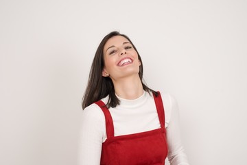 Joyful European woman having fun and laughs at good joke or sings wears casual clothes, standing against gray wall. Happy woman with long hair poses inddoors.