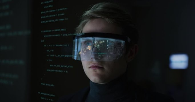 An young man is using futuristic innovative technology vr mask with augmented reality holograms on a black background. Concept of future,innovation, immersive technology, gaming,virtual reality