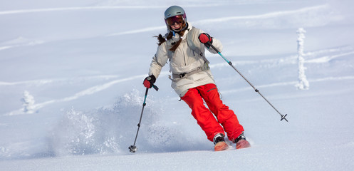 Girl On the Ski. a skier in a bright suit and outfit with long pigtails on her head rides outside...