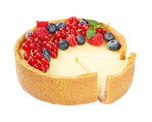 Cheesecake with fresh red currants, raspberries, blueberries and mint leaves isolated on white background.