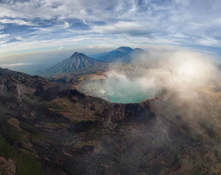 Spectacular aerial view of Mount Ijen volcano on East Java with sulfur blue acid lake and smoke erupting from the crater