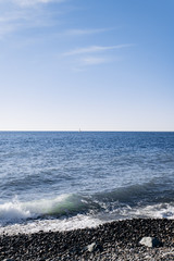 A white crested wave crashes on black lava rocks
