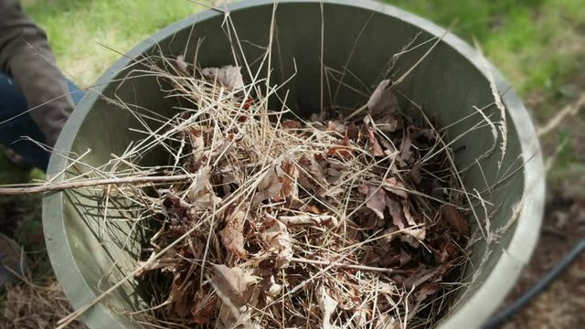Slow Motion of Dumping Spring Garden Waste in Trash Can.