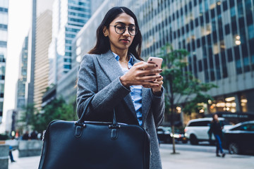 Focused young female typing on smartphone outside in New York