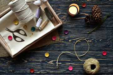 Sewing materials and burning candle on a dark wooden background. Top view. Close-up. Flat lay.