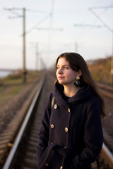Obraz premium Girl walks on railway rails in a coat - travel, lifestyle