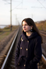 Obraz premium Girl walks on railway rails in a coat - travel, lifestyle