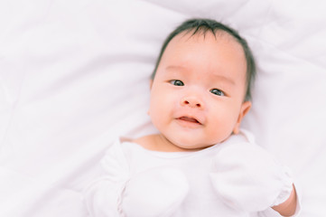 Smiling baby boy lying on a  white bed, Family morning at home,Children hygiene.