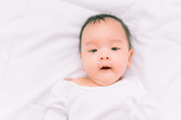 Smiling baby boy lying on a  white bed, Family morning at home,Children hygiene.
