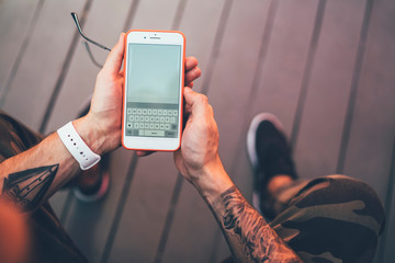 Faceless guy chatting with friend using mobile