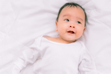 Smiling baby boy lying on a  white bed, Family morning at home,Children hygiene.