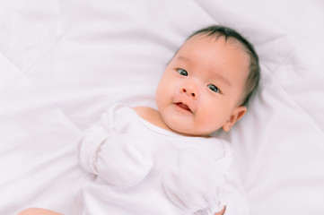 Smiling baby boy lying on a  white bed, Family morning at home,Children hygiene.