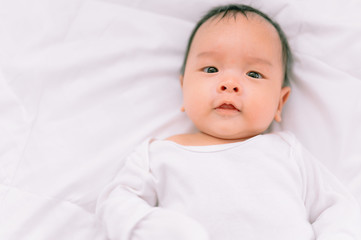Smiling baby boy lying on a  white bed, Family morning at home,Children hygiene.