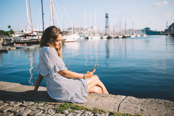 Carefree female browsing phone relaxing at waterfront