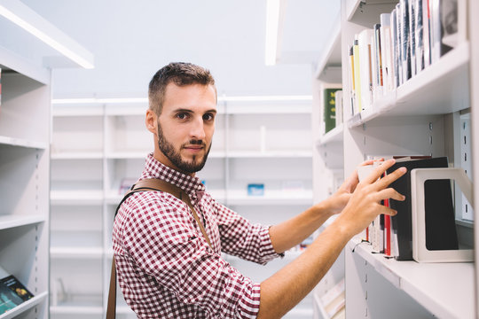 Handsome man choosing book in library