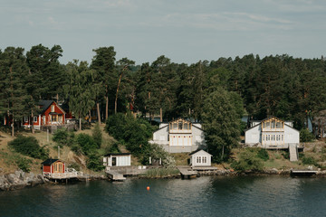 Obraz premium A big village on the seashore between trees in the forest on a sunny day.