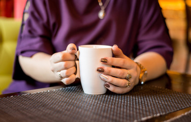 Girl drinking coffee from a mug. hands holding a hot Cup of coffee or tea in the morning. Cup in women's hands