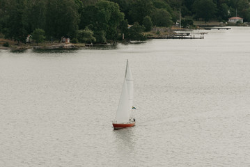 A red and white sailing yacht in the calm bay in the sunny afternoon