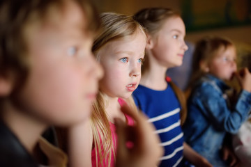 Four cute kids watching a movie at home. Children having fun in front of the TV. Kids playing video games in dark room.