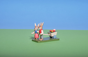 Two rabbits pull a cart with coloured eggs