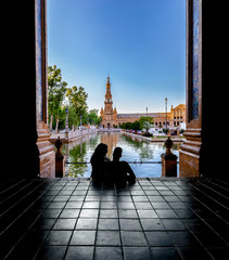Naklejka premium Silhouettes of young couple enjoying the sunset in the famous Spain Square (Plaza de Espana). Seville, Spain.