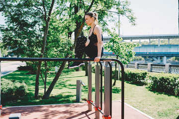 Young sportswoman doing parallel bar exercises in park